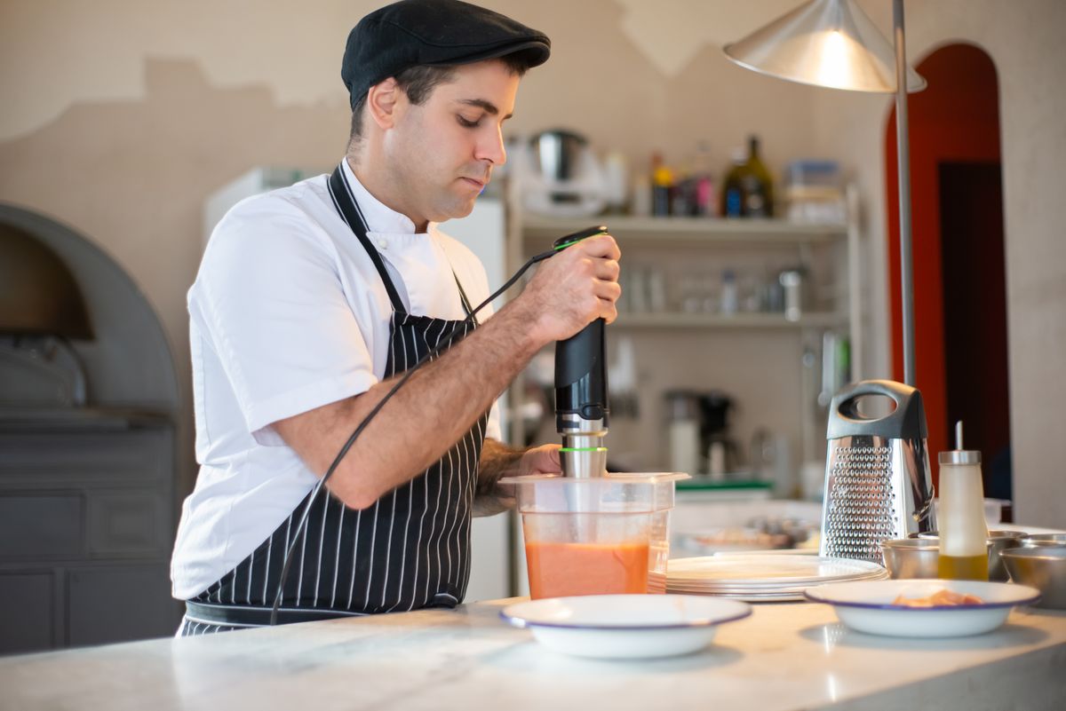 Persona trabajando de pie en una cocina.